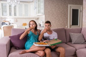 Young Couple Watching Television and Eating Pizza